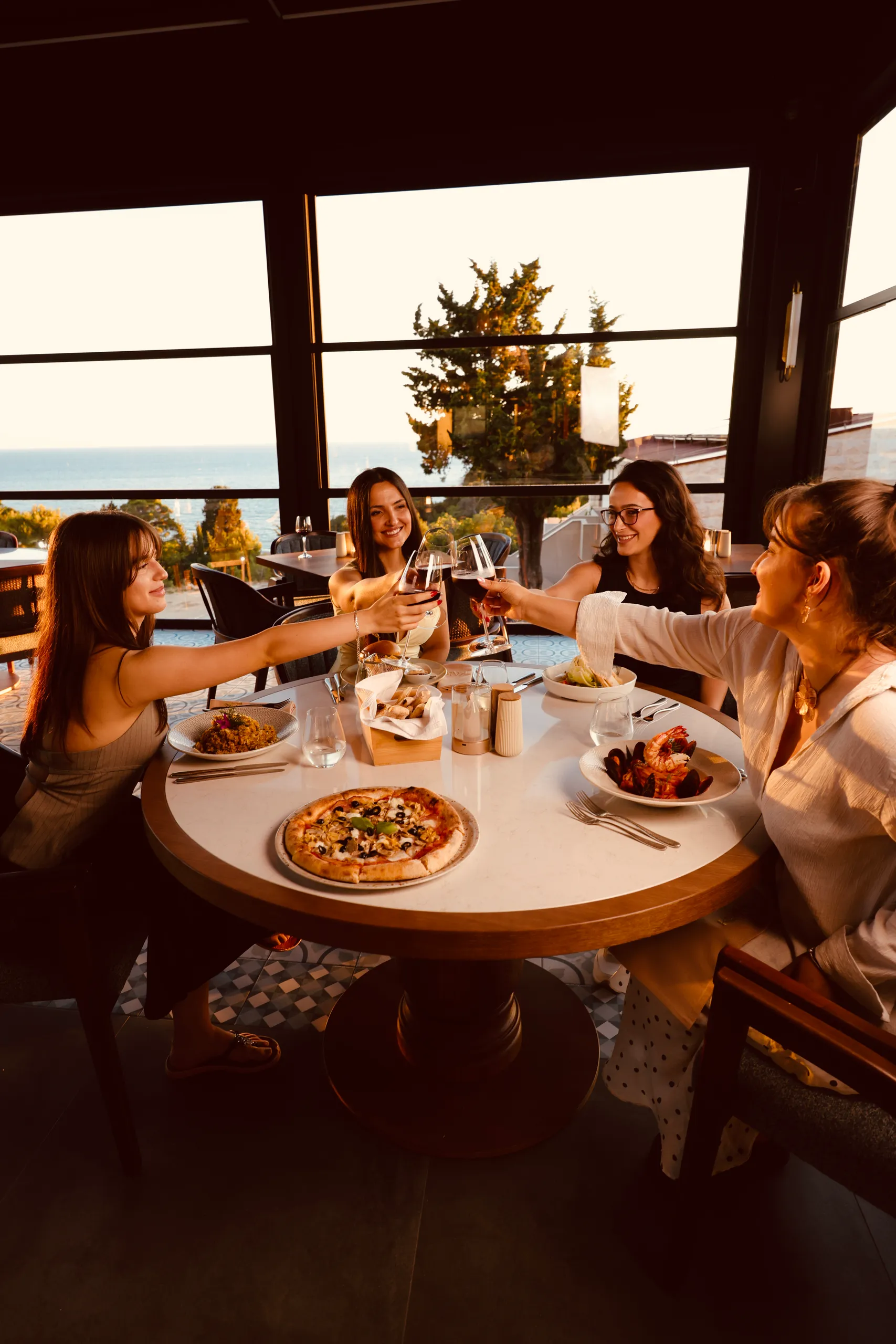 Guests raising a toast at a KALO table as the sun sets over the Adriatic.